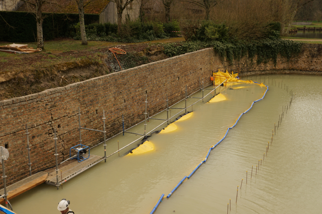 Batardeau souple installé dans les douves du château de Chamerolles avant pompage, vue depuis le pont Levi