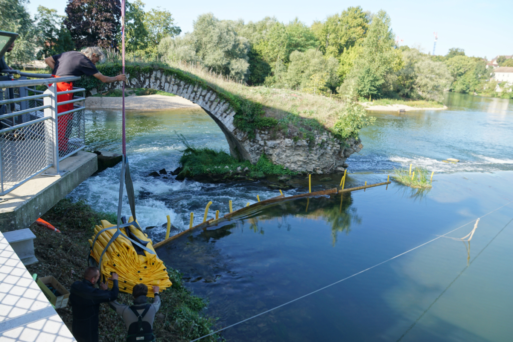 Dépose par grue de batardeaux Water-Gate repliés en rive du Doubs à Dole, en amont du pont roman